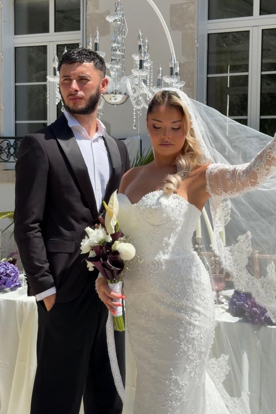 Mariés devant un lustre en cristal, dans la cour d'un château