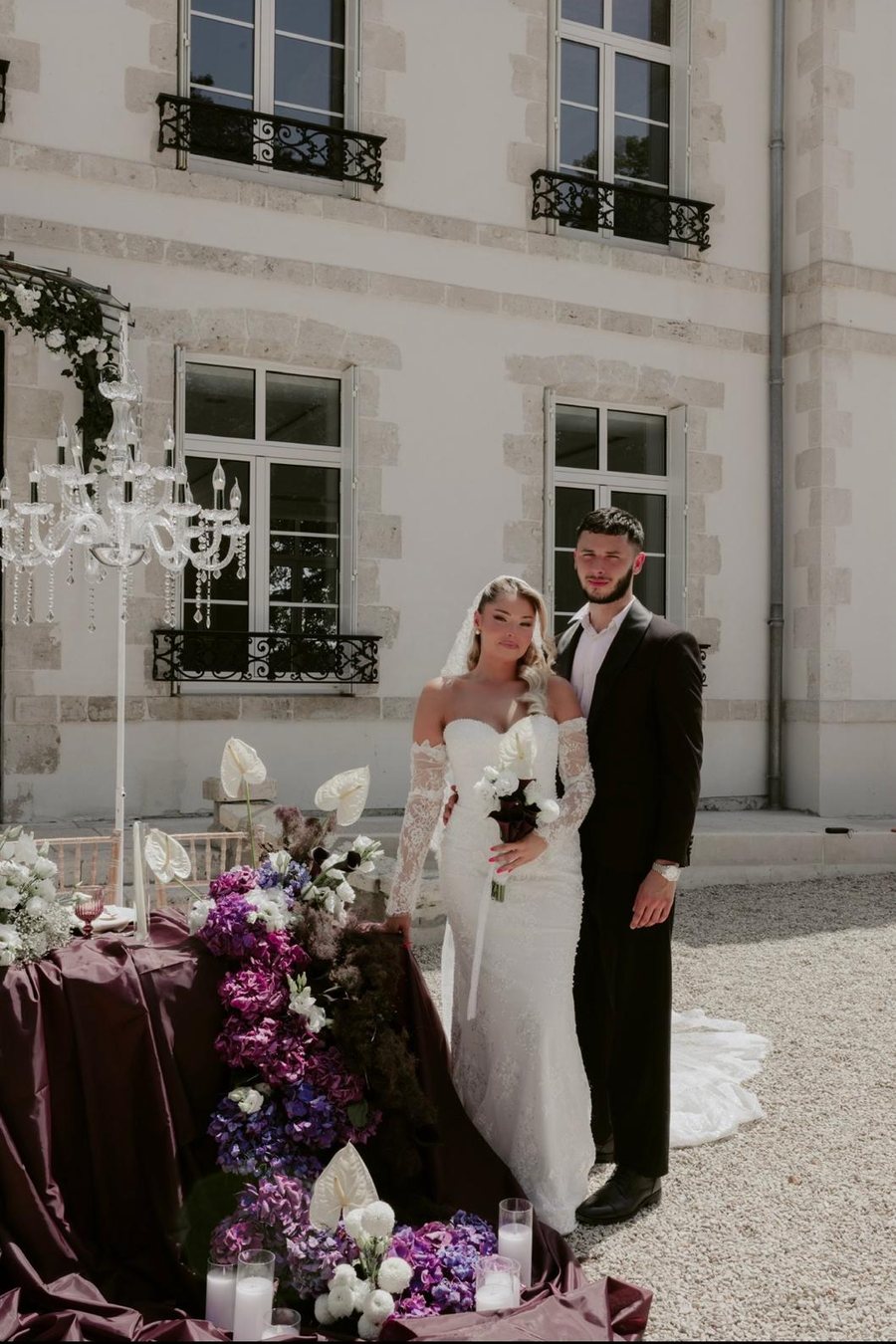 Mariés devant la façade d'un château, décor de fleurs pourpres